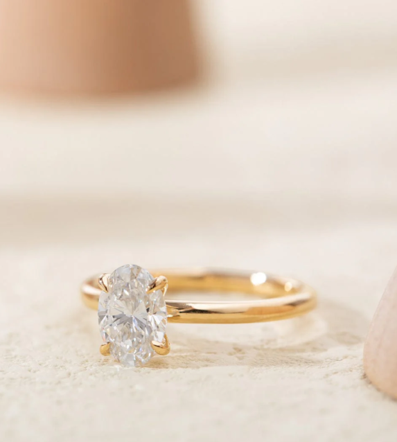 A close-up of a gold ring with a large oval-shaped diamond set in the center.